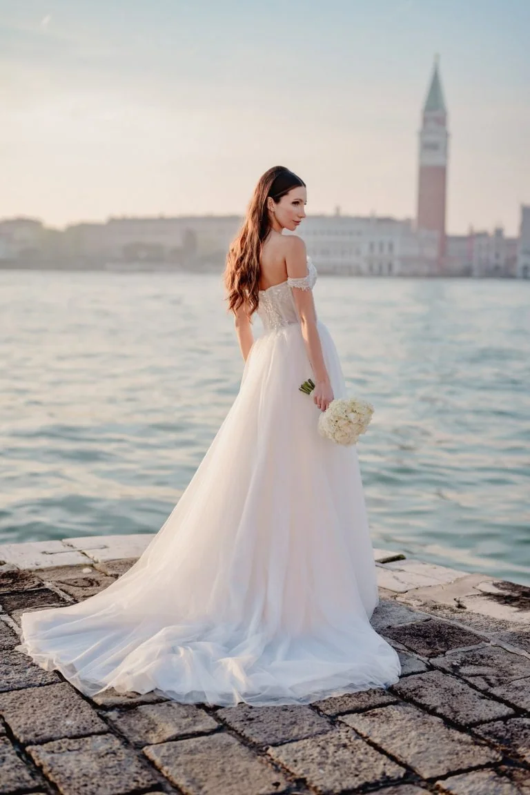 A bride posing elegantly on the banks of San Giorgio Maggiore in Venice – elopement photography Venice.