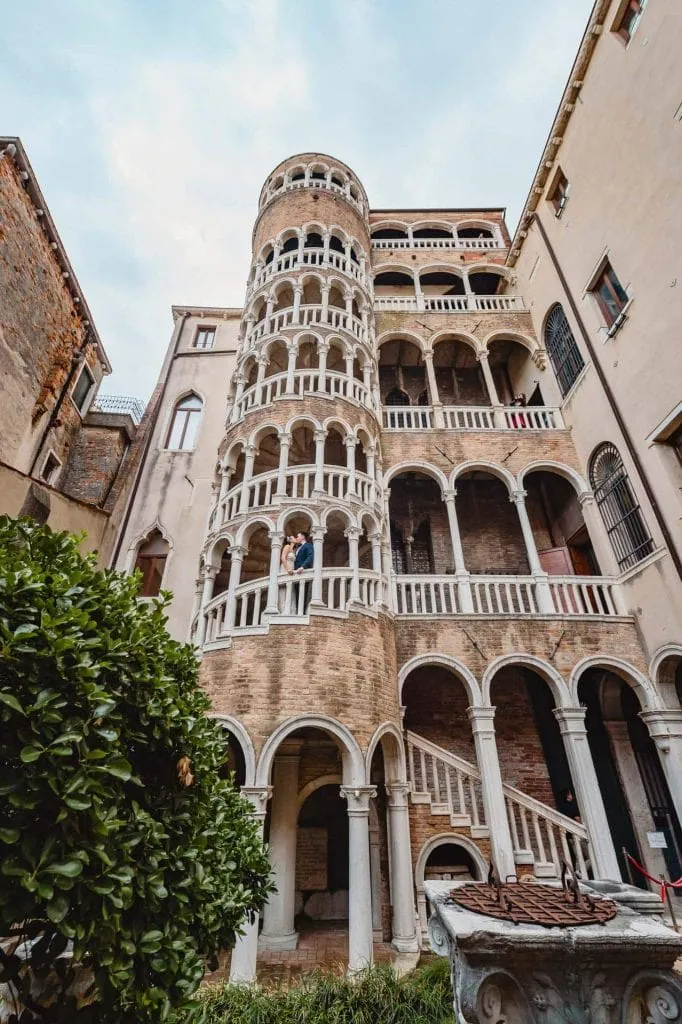 Couple posing outside the iconic Scala Contarini del Bovolo in Venice – Venice Wedding Photography Engagement.