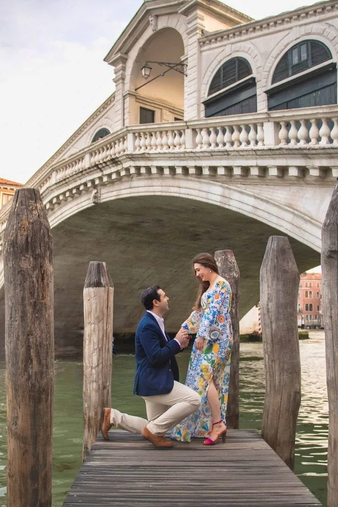 A man on one knee proposing to his partner in front of the Bridge of Sighs in Venice – proposal photography Venice.