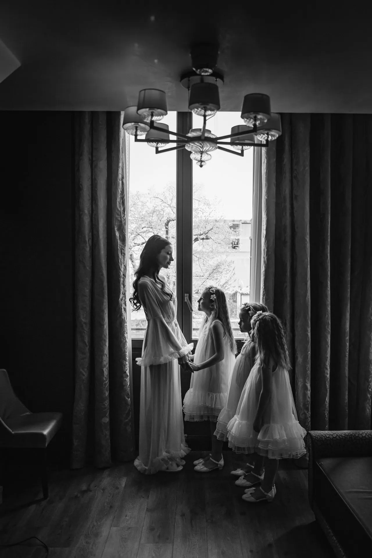 Elegant bride holding hands with flower girl in a hotel room ahead of wedding in Venice.