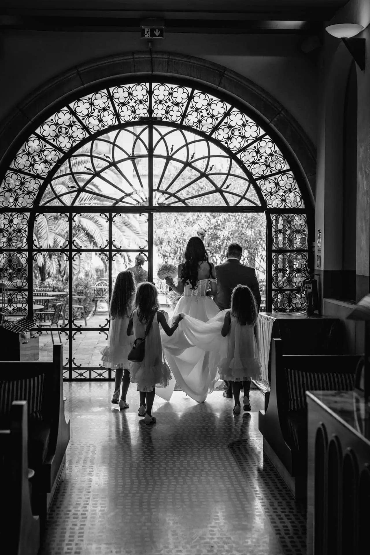 Wedding couple walking through ornate arched window in Venice.