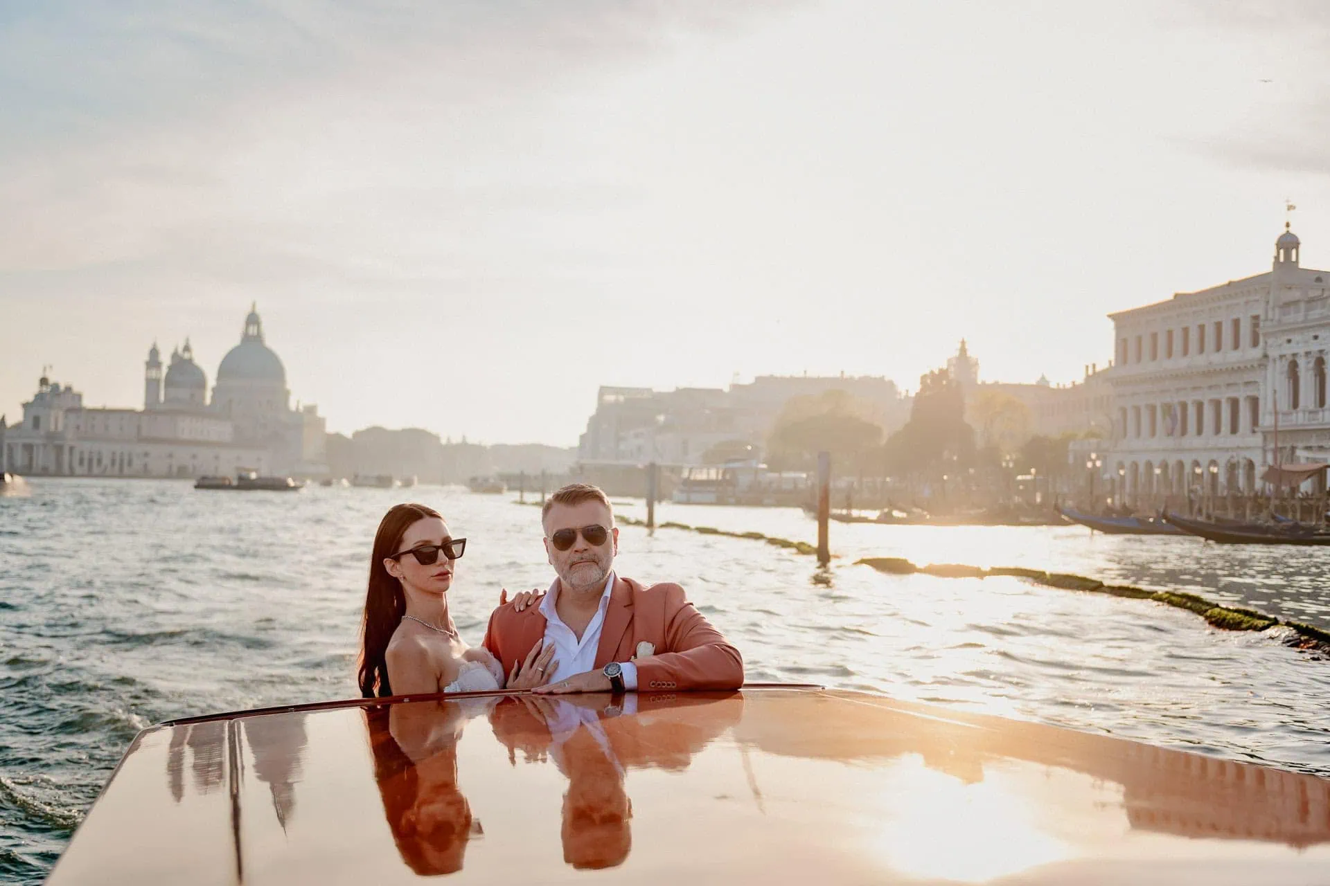 Elegant couple enjoying a romantic boat ride in Venice at sunset, capturing love and scenic views.