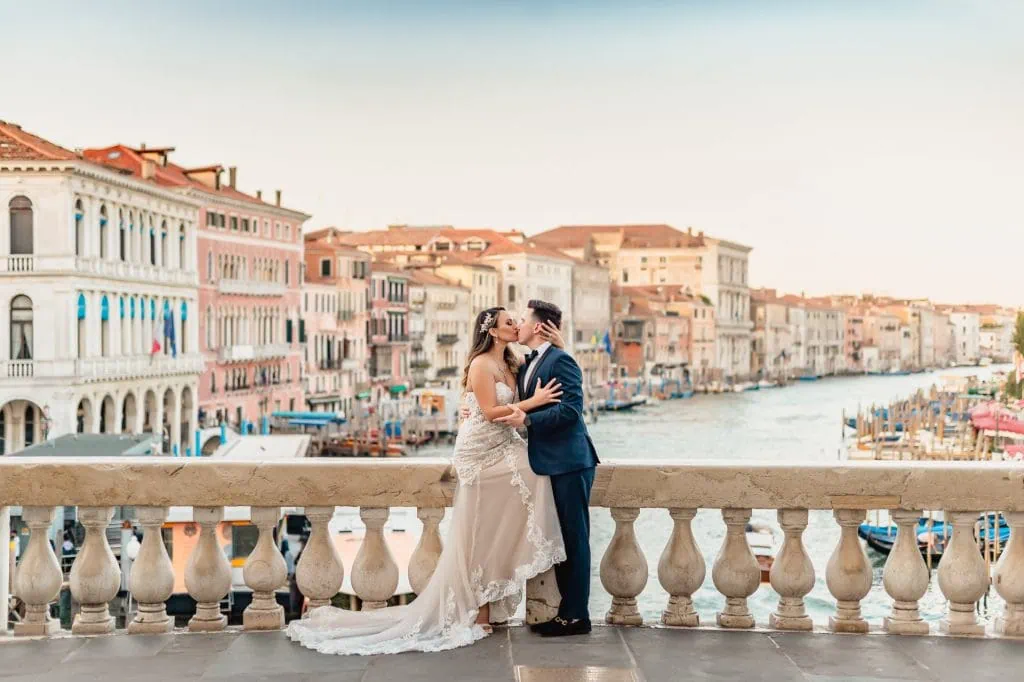Bride and groom pose at sunrise on the empty Rialto Bridge in Venice.