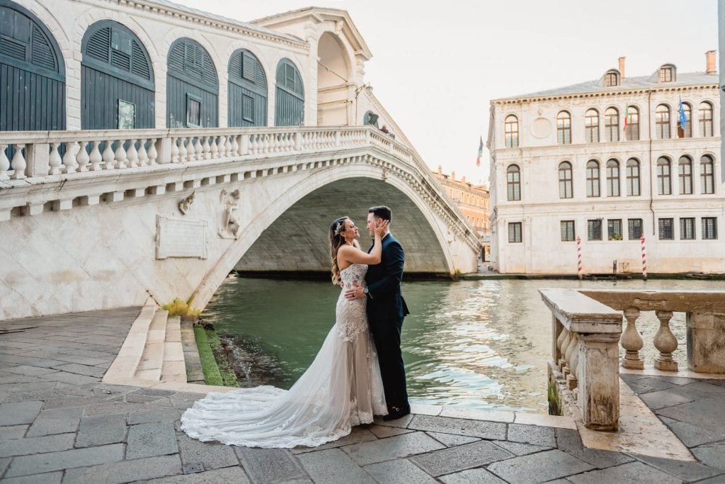 Bride and groom pose at sunrise on the empty Rialto Bridge in Venice.