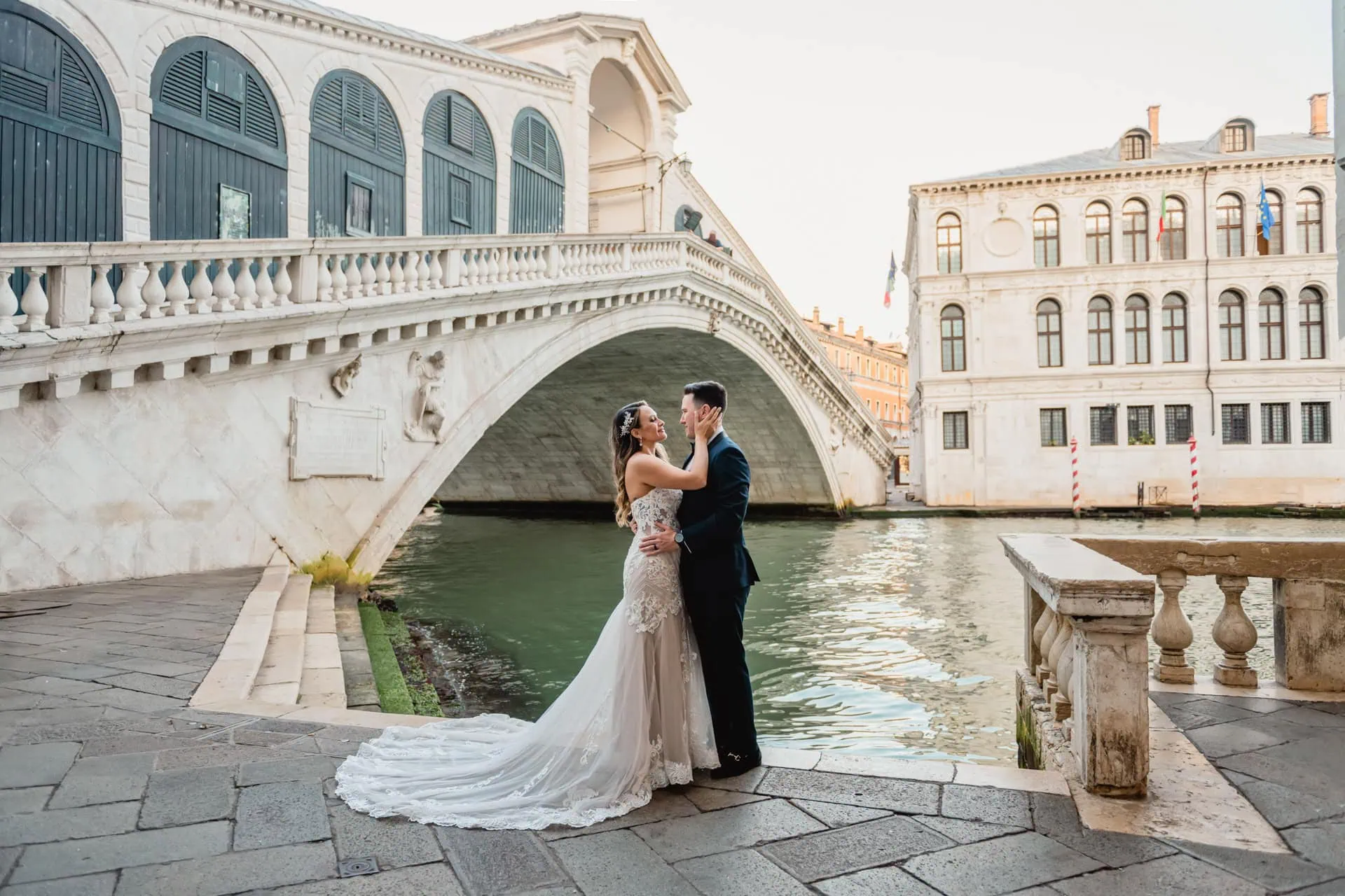 Bride and groom pose at sunrise on the empty Rialto Bridge in Venice.