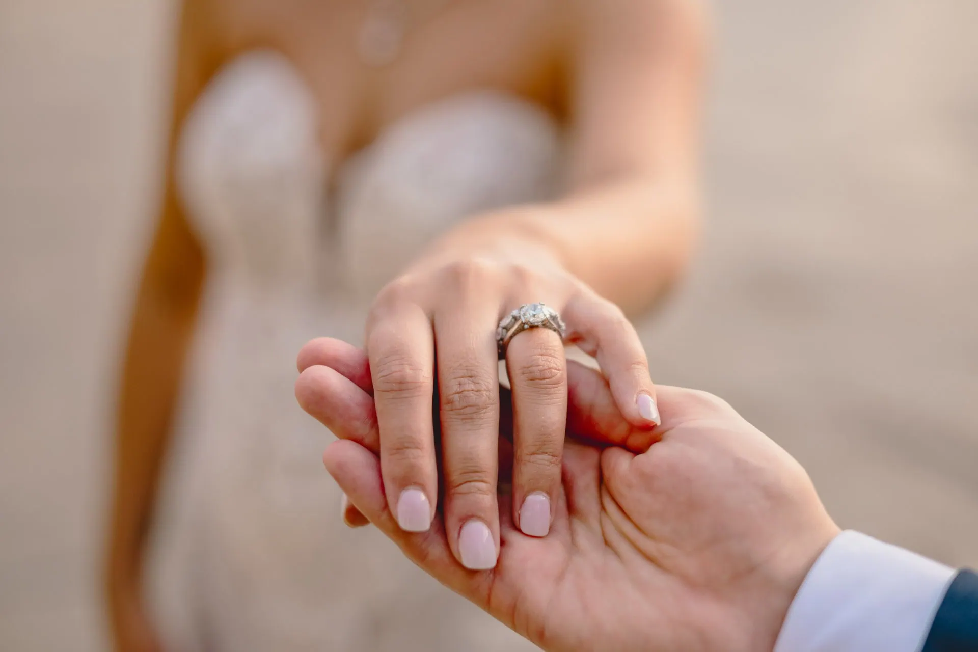 Bride and groom walk hand in hand through an empty Piazza San Marco, with the Bridge of Sighs in the background.