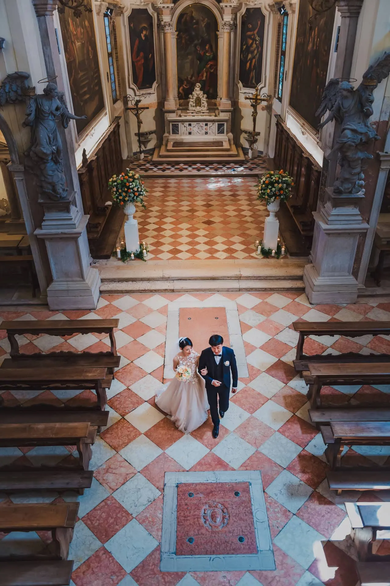 Venice wedding ceremony in a historic church with ornate architecture and floral decor.