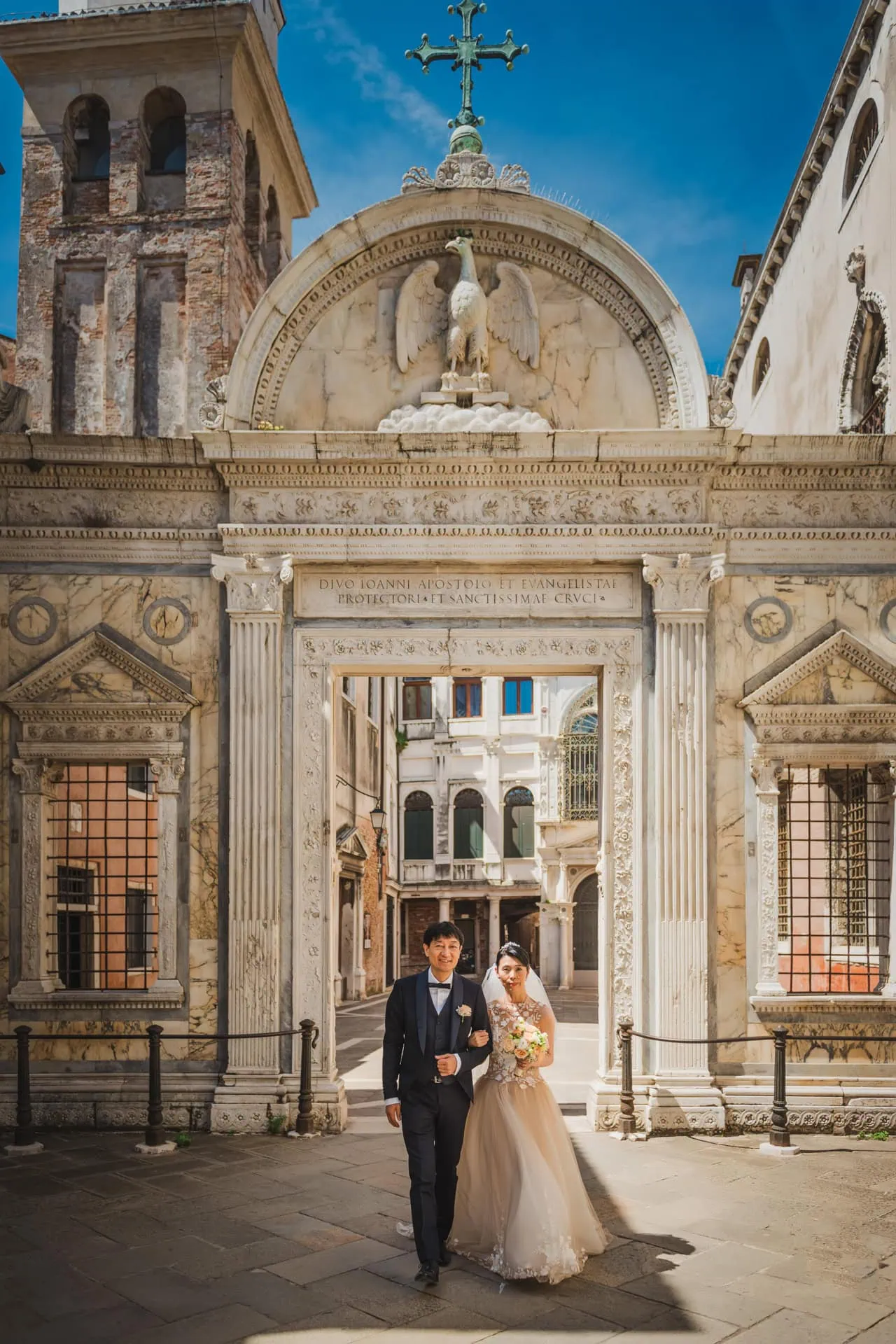 Venice wedding couple walking through historic archway with ornate architecture.