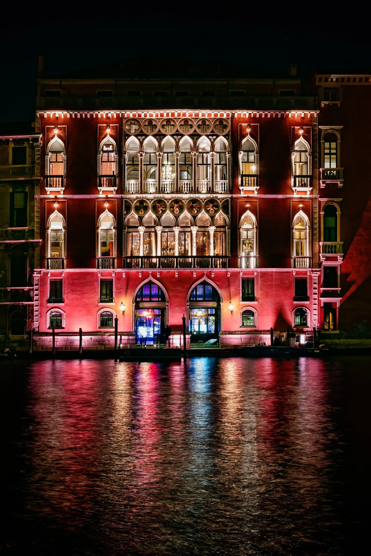 Venice historic building illuminated at night reflected in water.