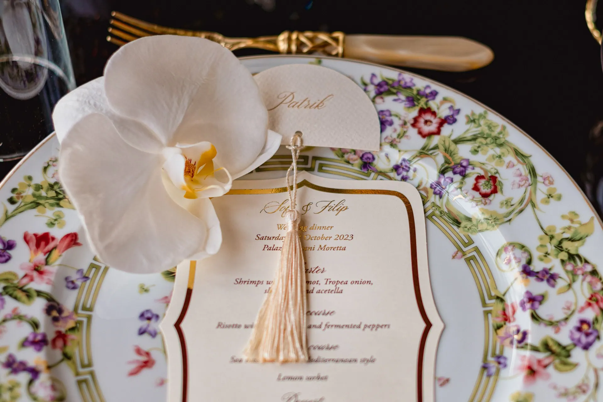 Elegant wedding place setting with floral china, orchid decoration, and personalized menu card in Venice.