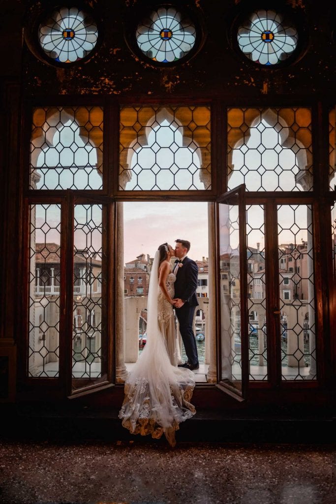 A couple sharing a romantic moment on the balcony of Ca’ Sagredo in Venice – venice photography wedding symbolic casagredo.