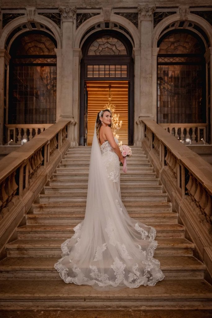 A bride gracefully posing on the grand staircase of Ca’ Sagredo – venice photography wedding symbolic casagredo.