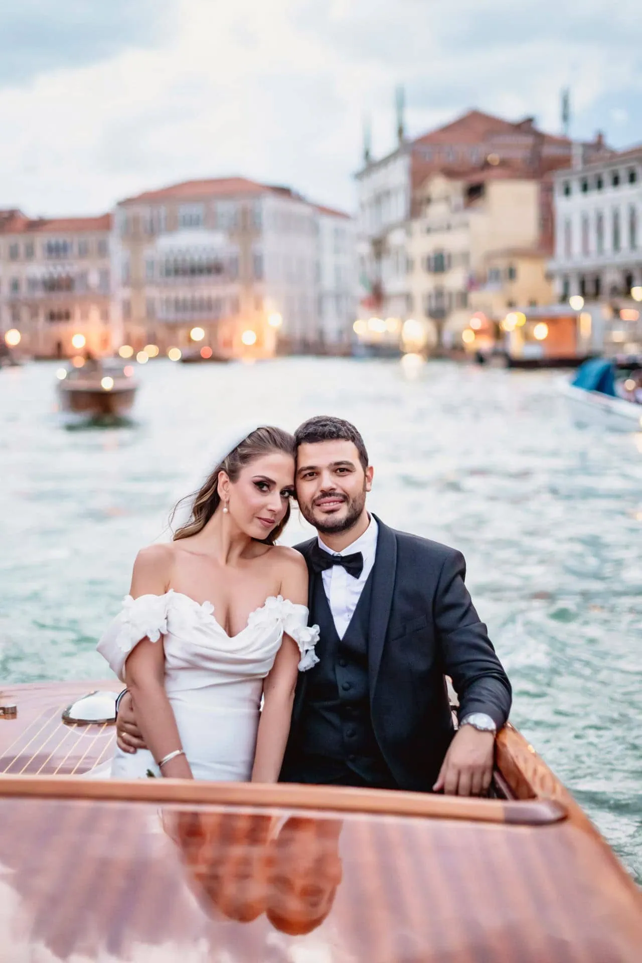 A beautiful couple enjoying a romantic ride in a Venetian water taxi after their wedding ceremony. Captured by a Venice wedding photographer.