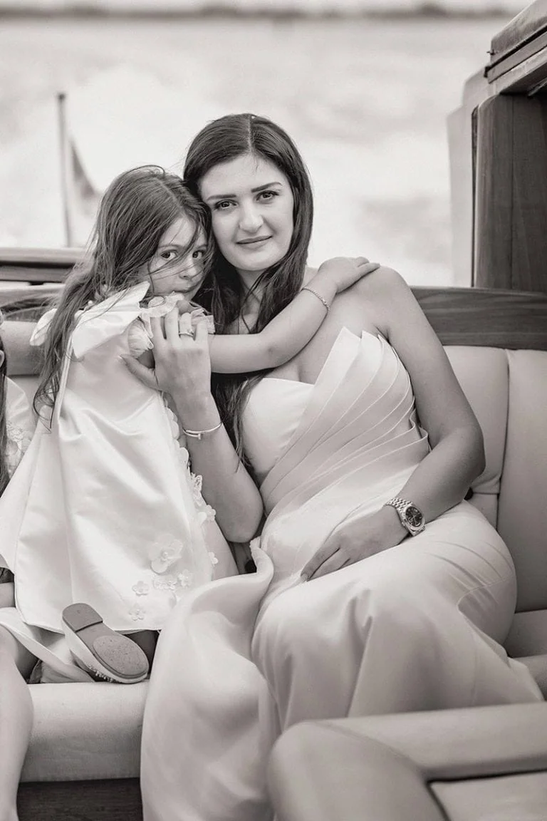 A bride and her daughter sharing a joyful moment in a Venetian water taxi – wedding photography Venice