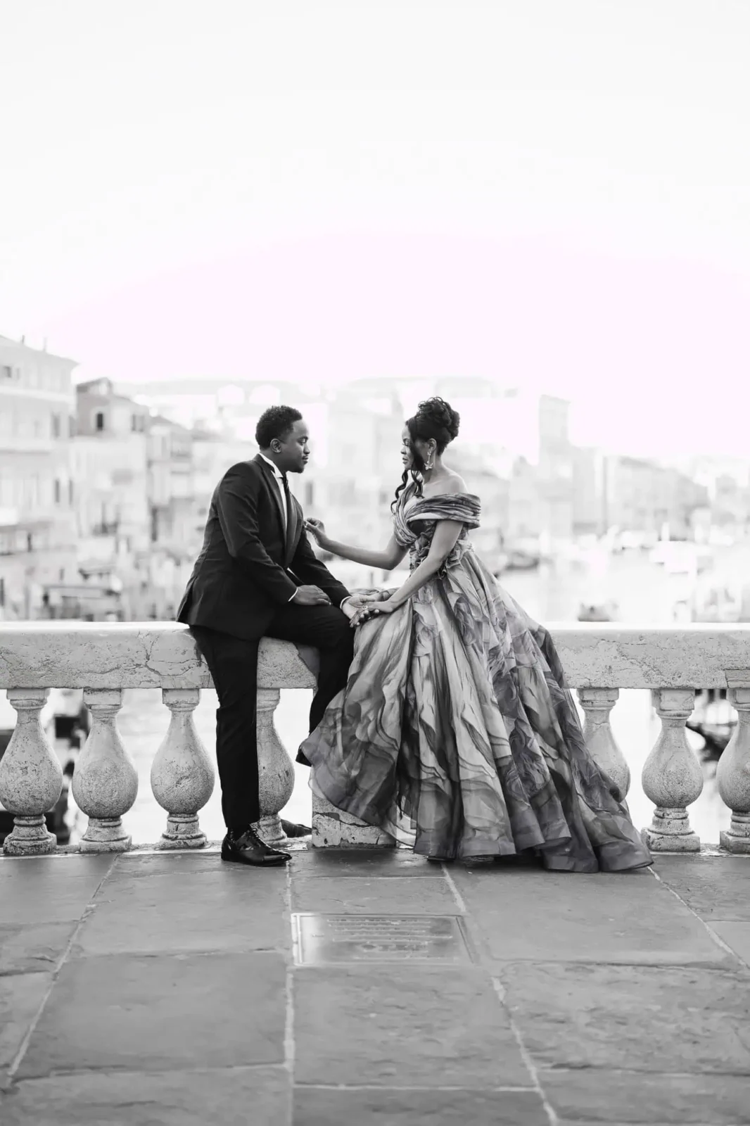 Elegant couple in wedding attire on a Venice canal balcony, romantic shot for engagement photos.
