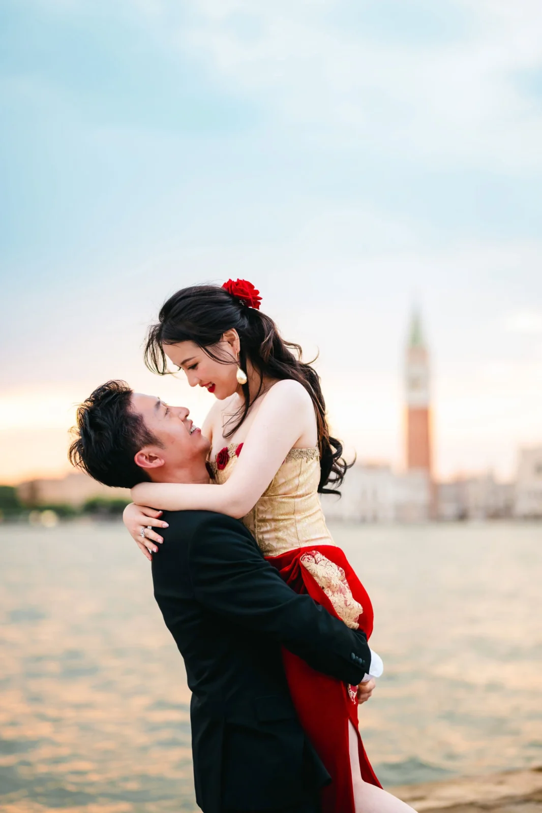 Romantic couple embracing in Venice at sunset, celebrating engagement with iconic city backdrop.