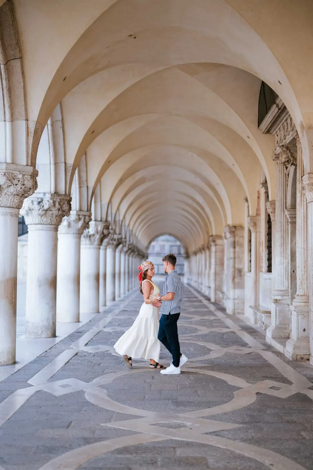 Venice couple dance under historic arches during engagement photoshoot.
