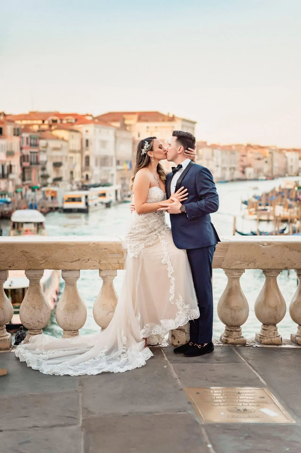 Bride and groom pose at sunrise on the empty Rialto Bridge in Venice.