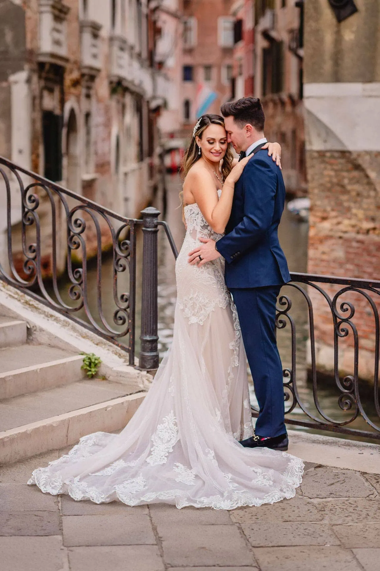 Bride and groom walk hand in hand through an empty Piazza San Marco, with the Bridge of Sighs in the background.