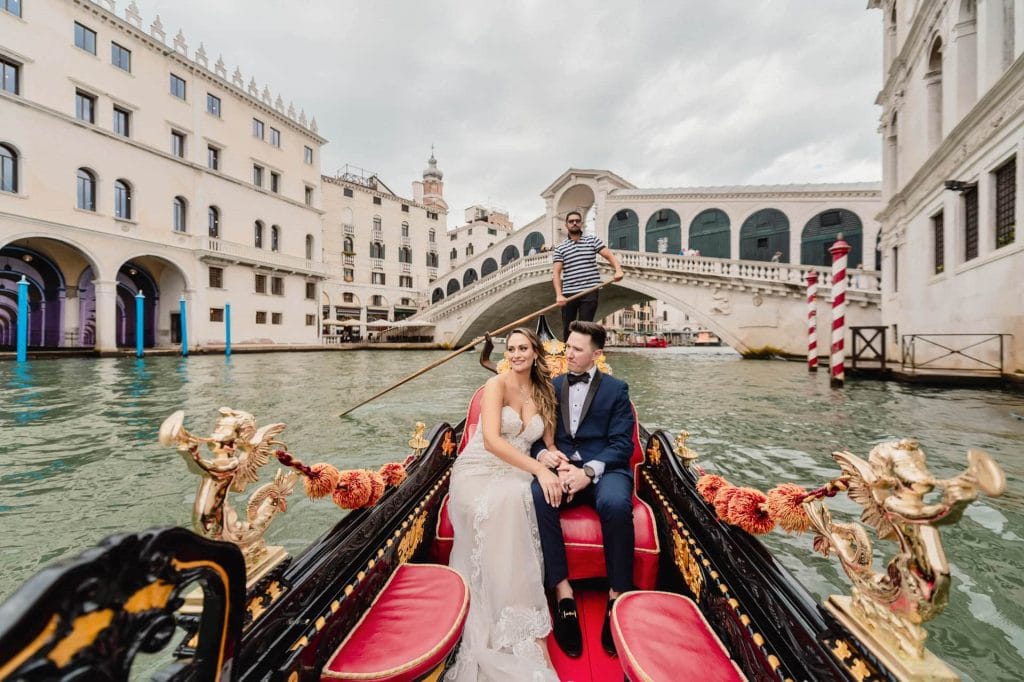 Bride and groom share a romantic gondola ride through Venice’s quiet canals.