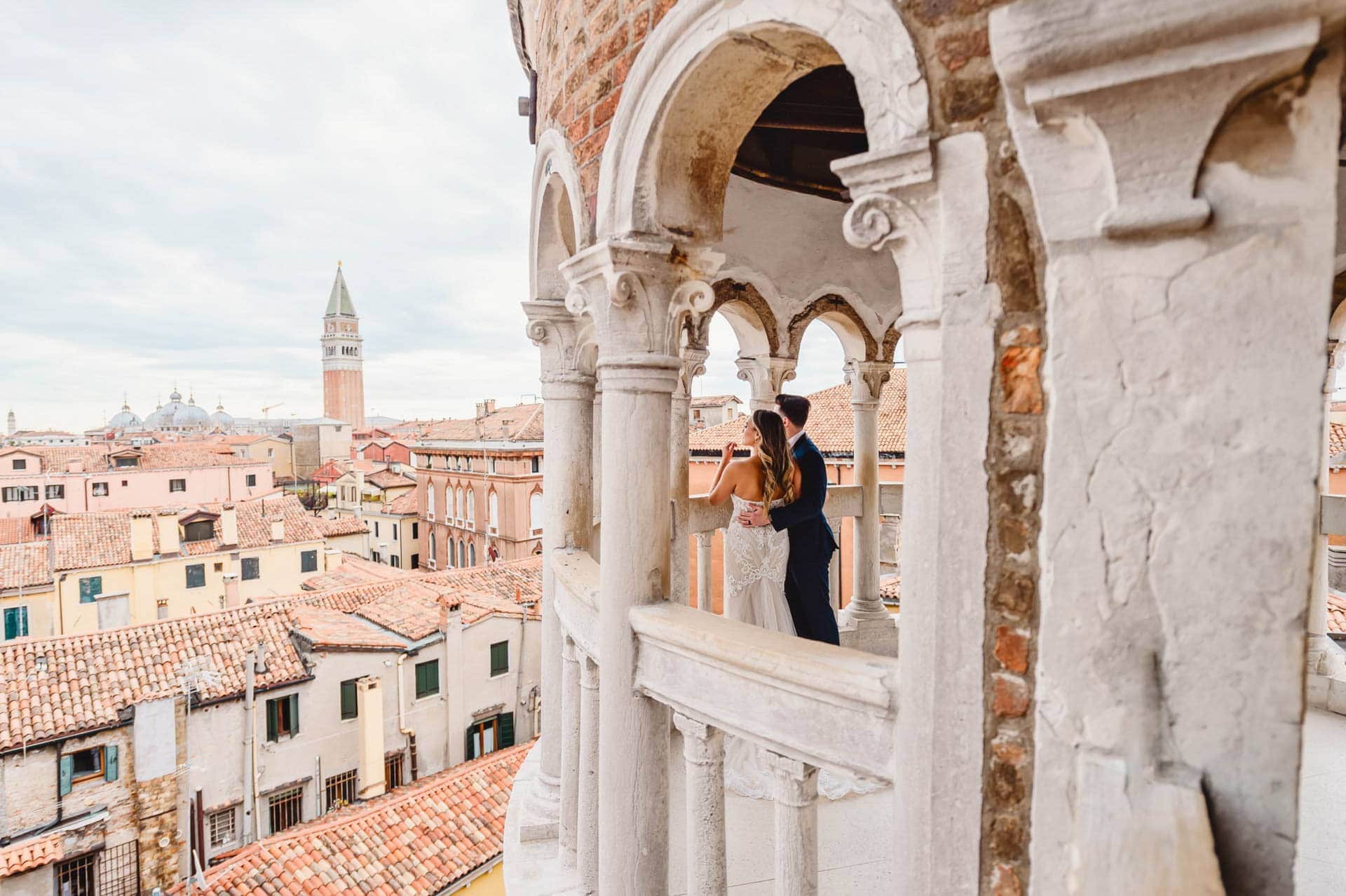 Bride and groom pose on the spiral staircase of Scala Contarini del Bovolo in Venice.