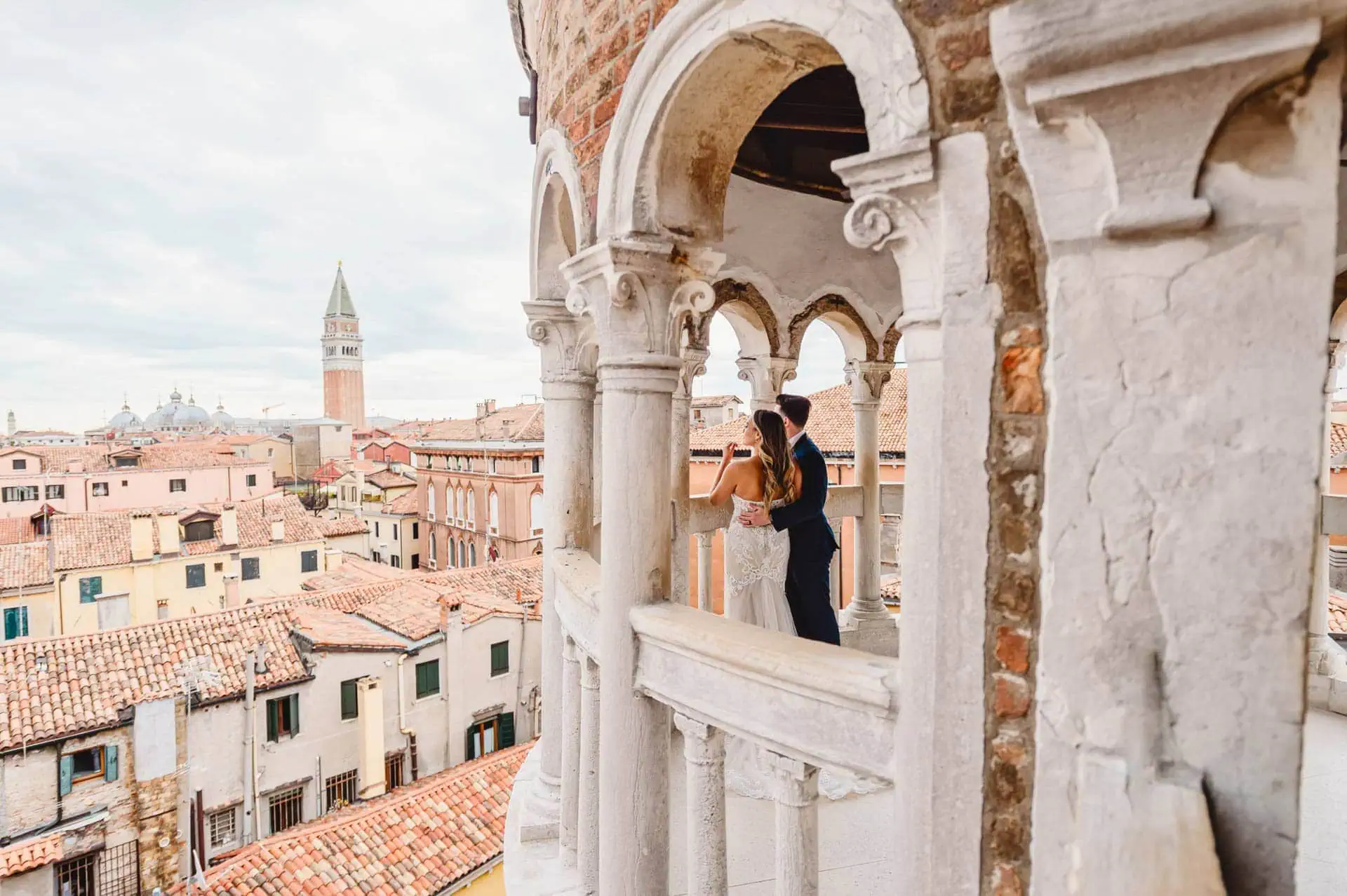Bride and groom pose on the spiral staircase of Scala Contarini del Bovolo in Venice.