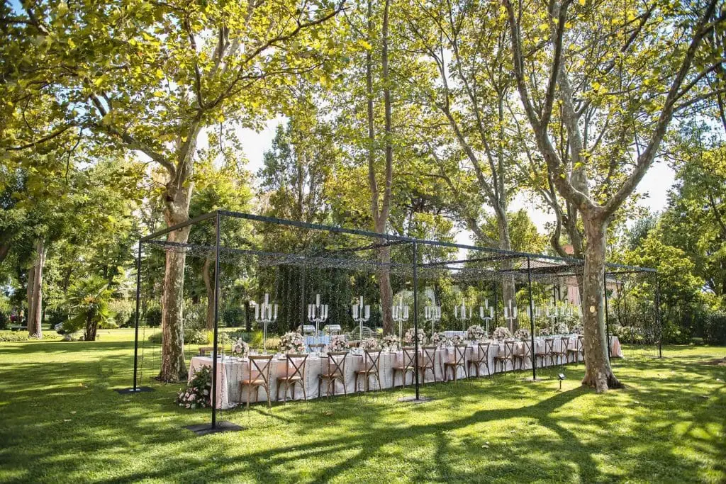 A couple during a symbolic wedding in Venice captured in the enchanting gardens of the Kempinski Hotel.