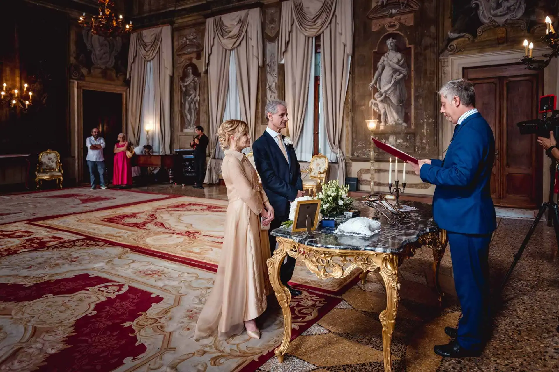 A couple during a symbolic wedding in Venice captured inside a luxurious private palace, surrounded by elegant decor.