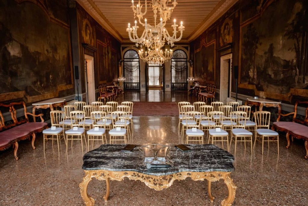 Elegant wedding table setting in a luxurious Venetian palace with floral arrangements and fine tableware.