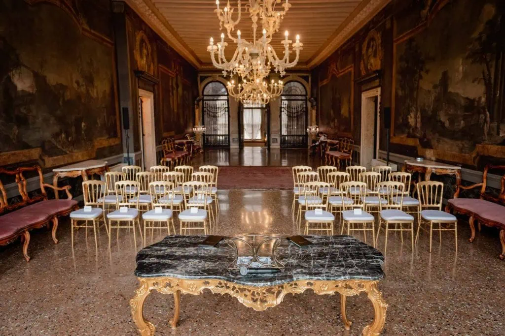 Elegant wedding table setting in a luxurious Venetian palace with floral arrangements and fine tableware.