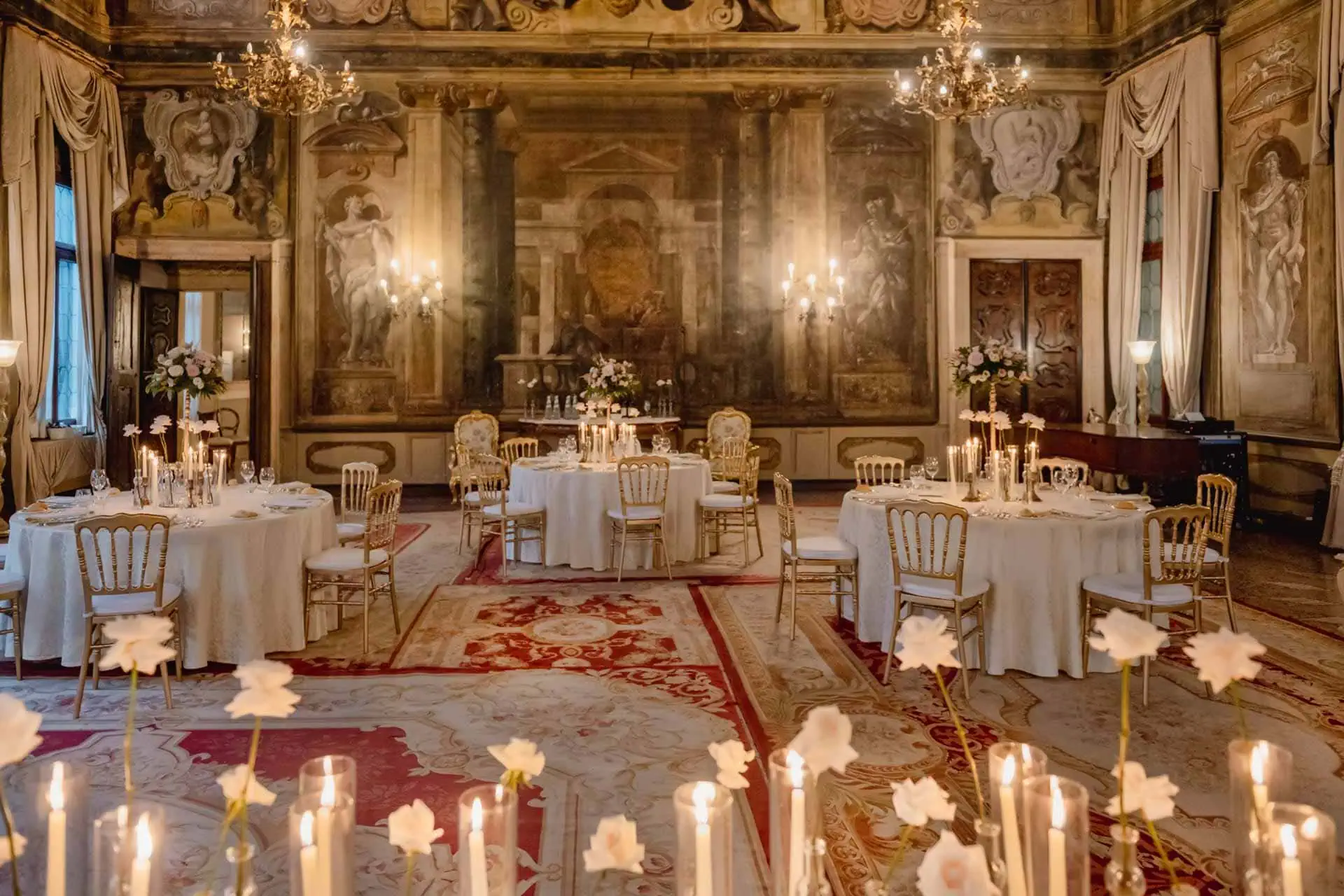 Elegant wedding table setting in a luxurious Venetian palace with floral arrangements and fine tableware.