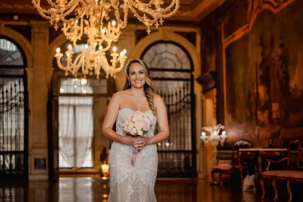 Bride and groom exchange vows in an ornate Venetian palace adorned with frescoes and sculptures.