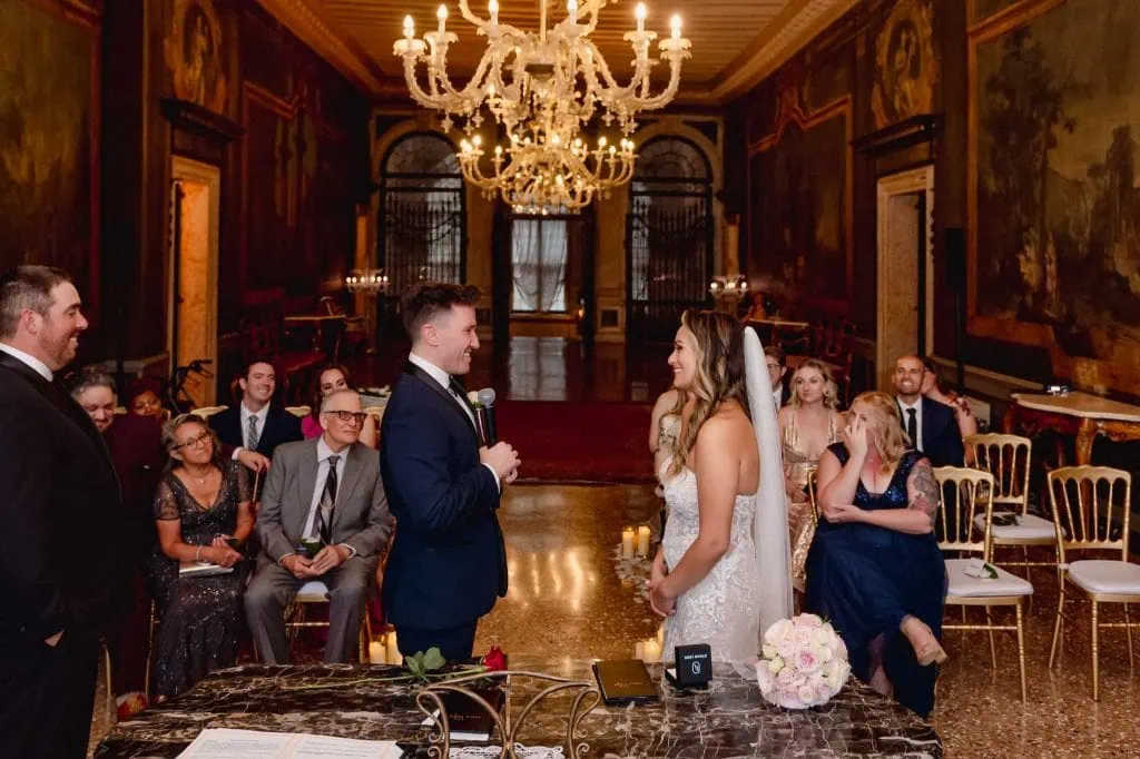Bride and groom exchange vows in an ornate Venetian palace adorned with frescoes and sculptures.