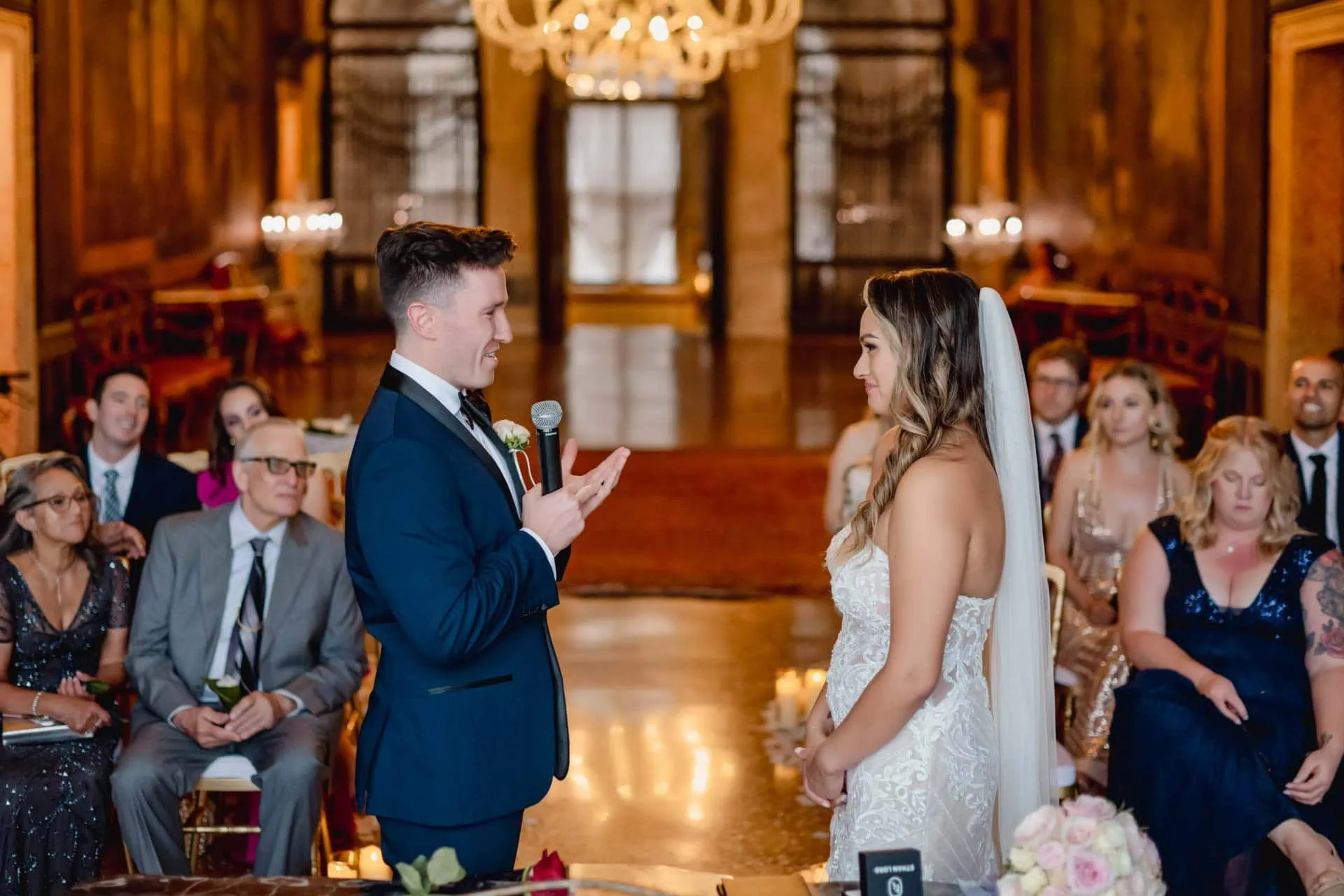 Bride and groom exchange vows in an ornate Venetian palace adorned with frescoes and sculptures.