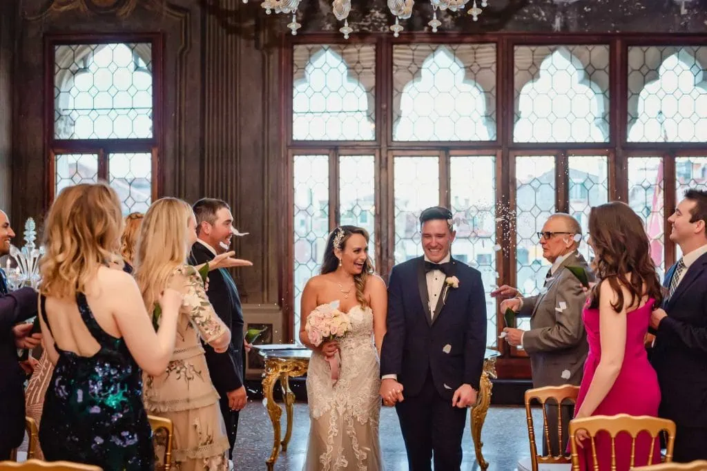 Bride and groom exchange vows in an ornate Venetian palace adorned with frescoes and sculptures.
