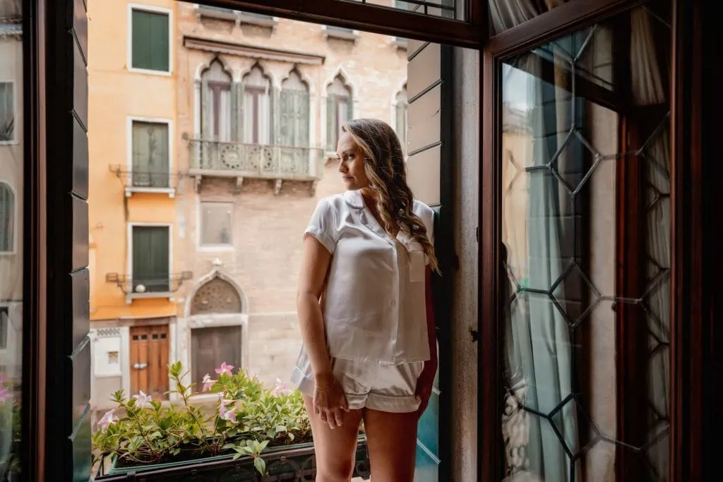 Bride and groom hold hands around a corner for their "first touch" moment in a luxurious Venetian hotel.