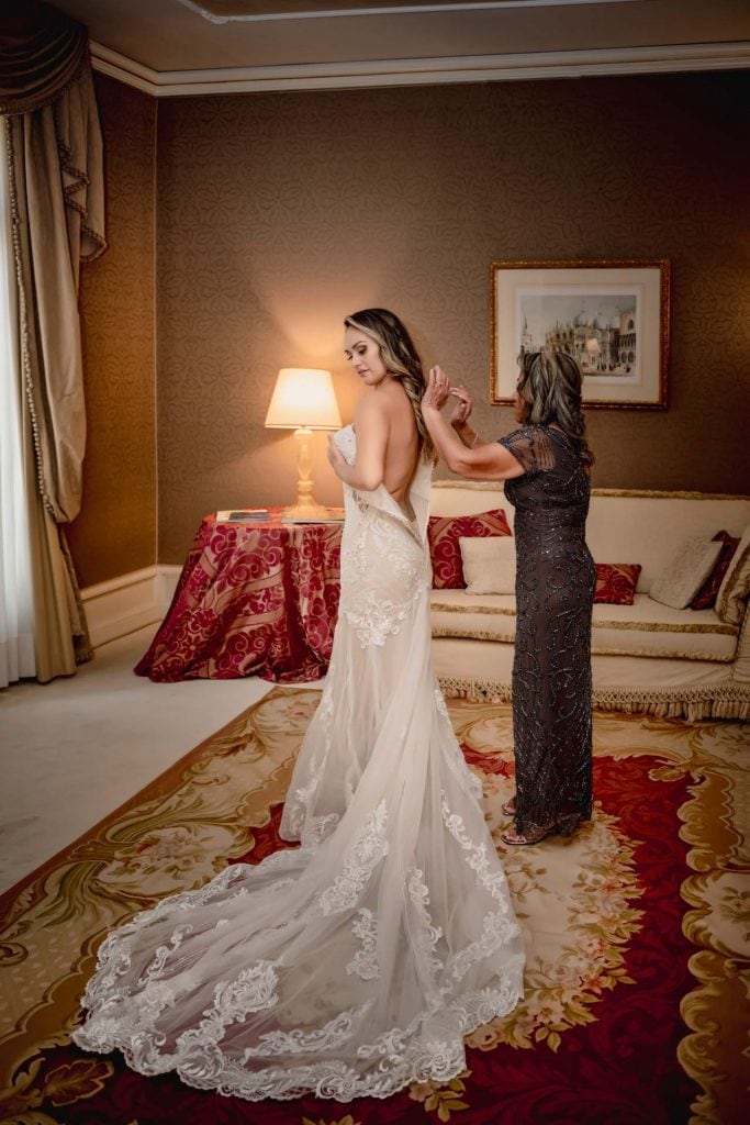 Bride and groom hold hands around a corner for their "first touch" moment in a luxurious Venetian hotel.