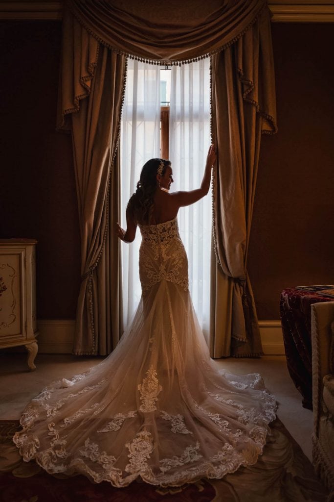 Bride and groom hold hands around a corner for their "first touch" moment in a luxurious Venetian hotel.