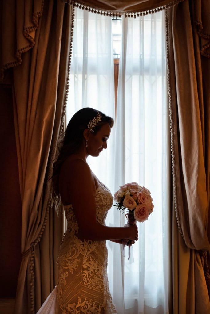 Bride and groom hold hands around a corner for their "first touch" moment in a luxurious Venetian hotel.