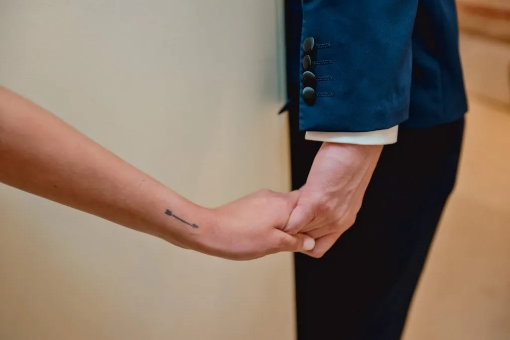 Bride and groom hold hands around a corner for their "first touch" moment in a luxurious Venetian hotel.