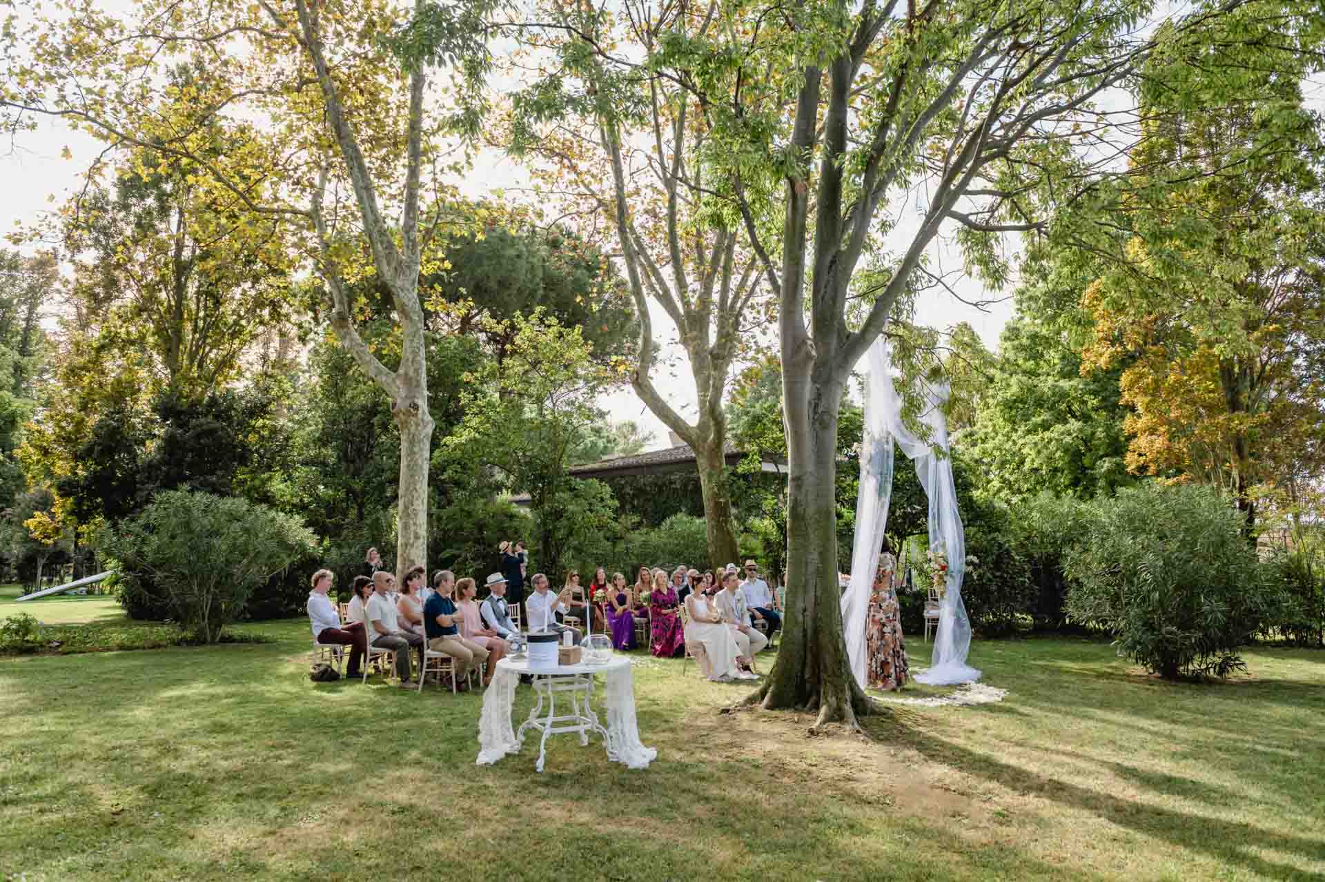 A couple during a symbolic wedding in Venice captured in the enchanting gardens of the Kempinski Hotel.