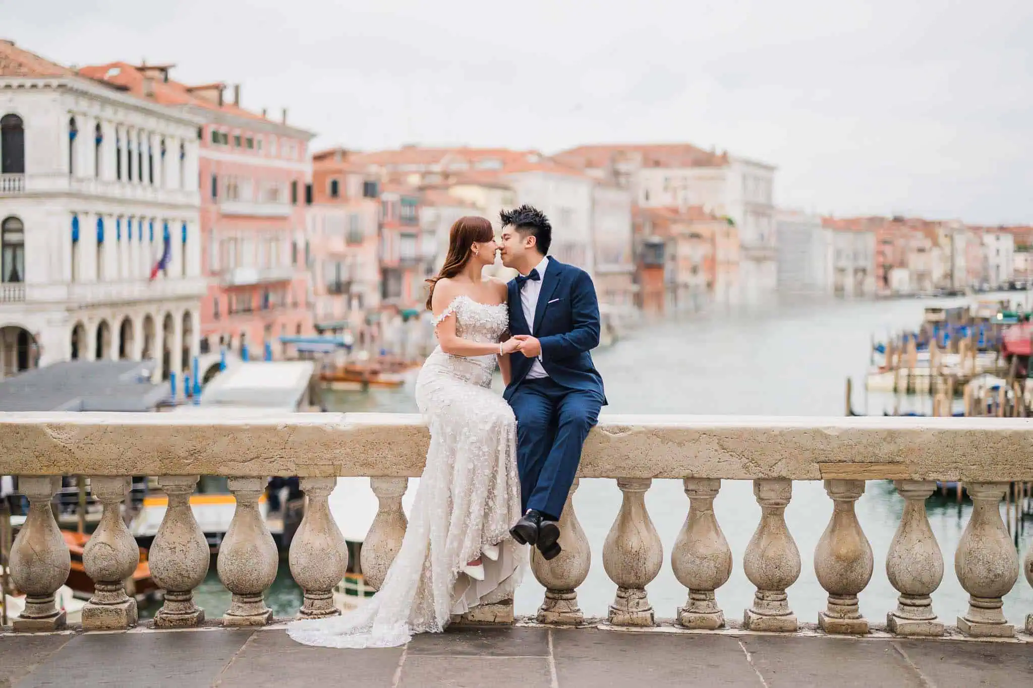 Romantic couple in wedding attire on Venice canal, colorful historic buildings in the background.