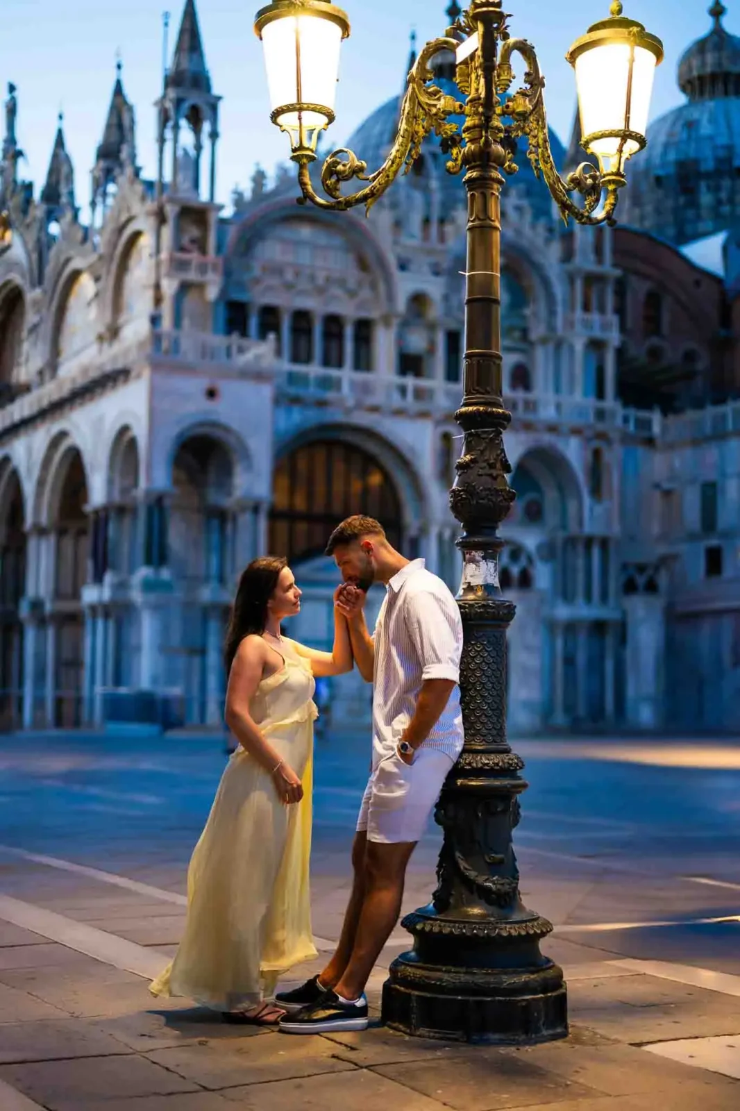 Romantic couple in Venice at dusk, proposal under ornate street lamp, elegant wedding and engagement photoshoot, historic architecture background.