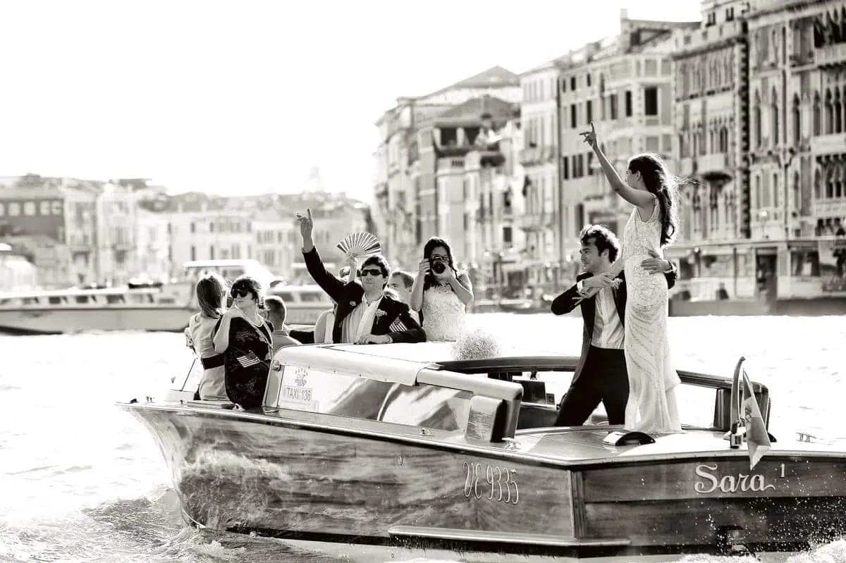Elegant couple celebrating on a gondola with friends in Venice for a wedding proposal.