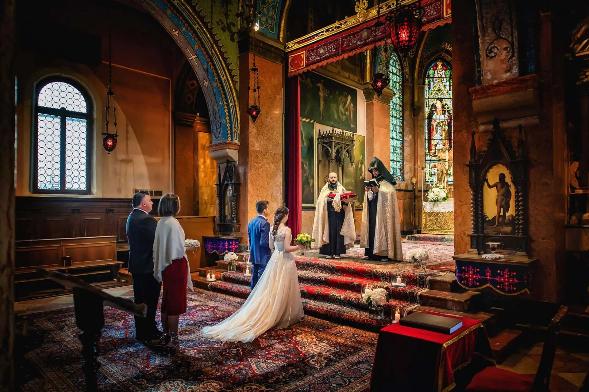 Venice wedding ceremony inside a historic church with colorful stained glass windows and ornate decorations.