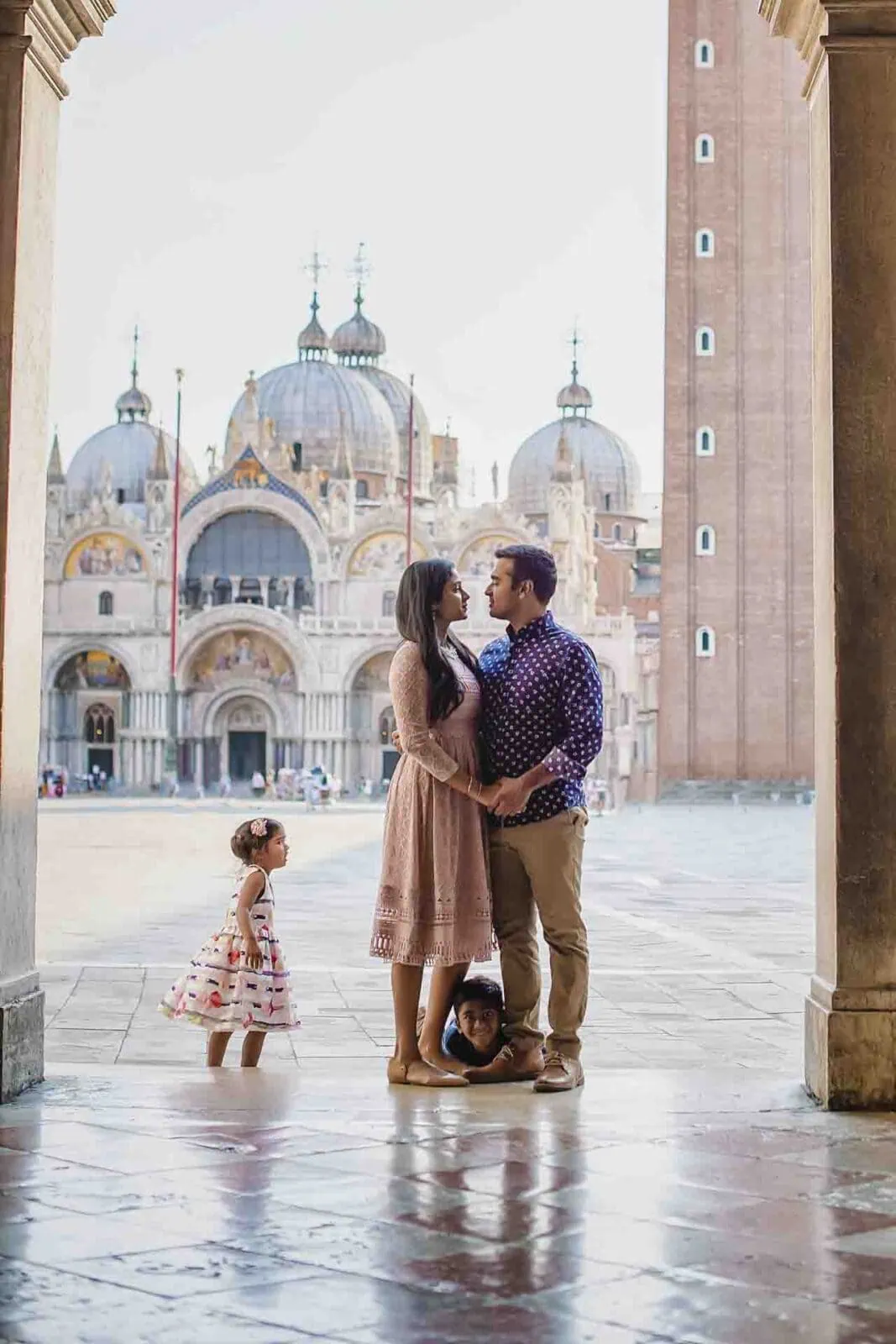 Parents holding hands with their daughter in St. Mark’s Square, Venice.