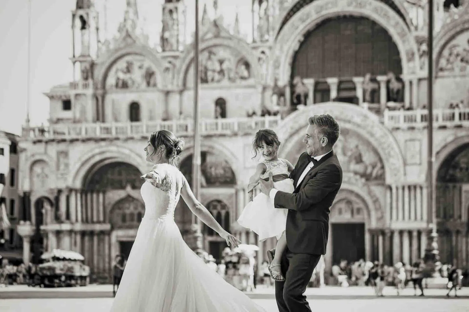Parents holding hands with their daughter in St. Mark’s Square, Venice.