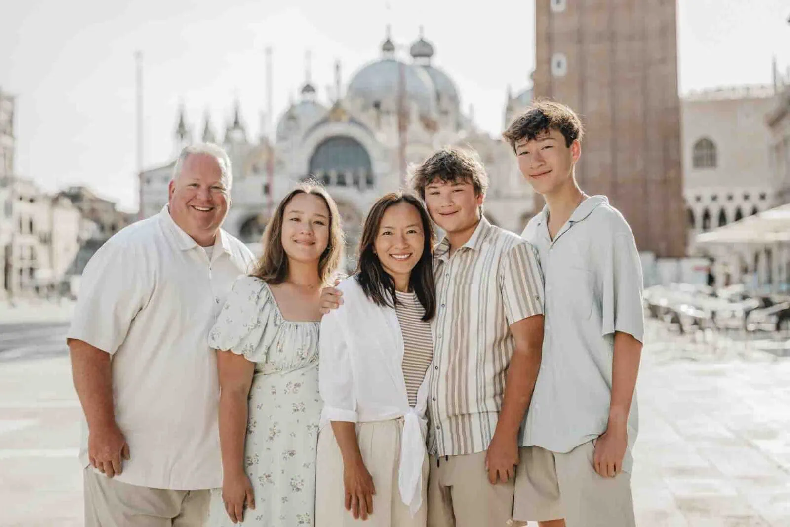 A happy family posing in St. Mark’s Square, Venice, with the Basilica in the background.