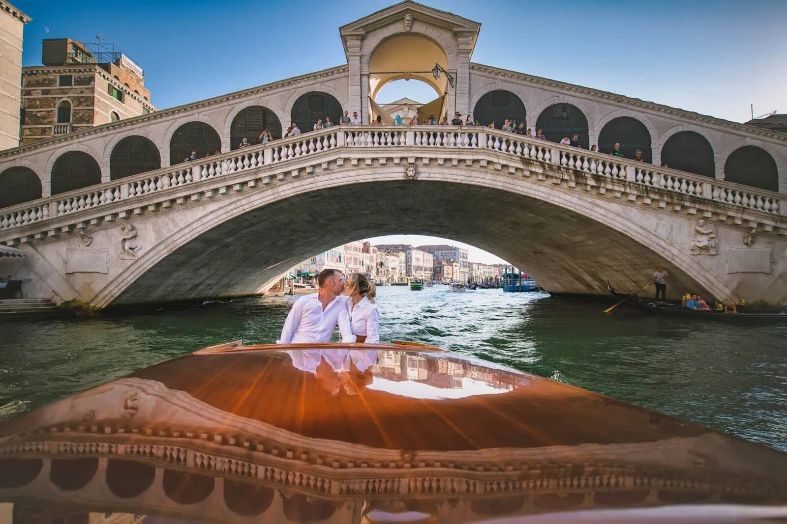 Romantic engagement photos in Venice featuring a couple in a water taxi under the Rialto Bridge.