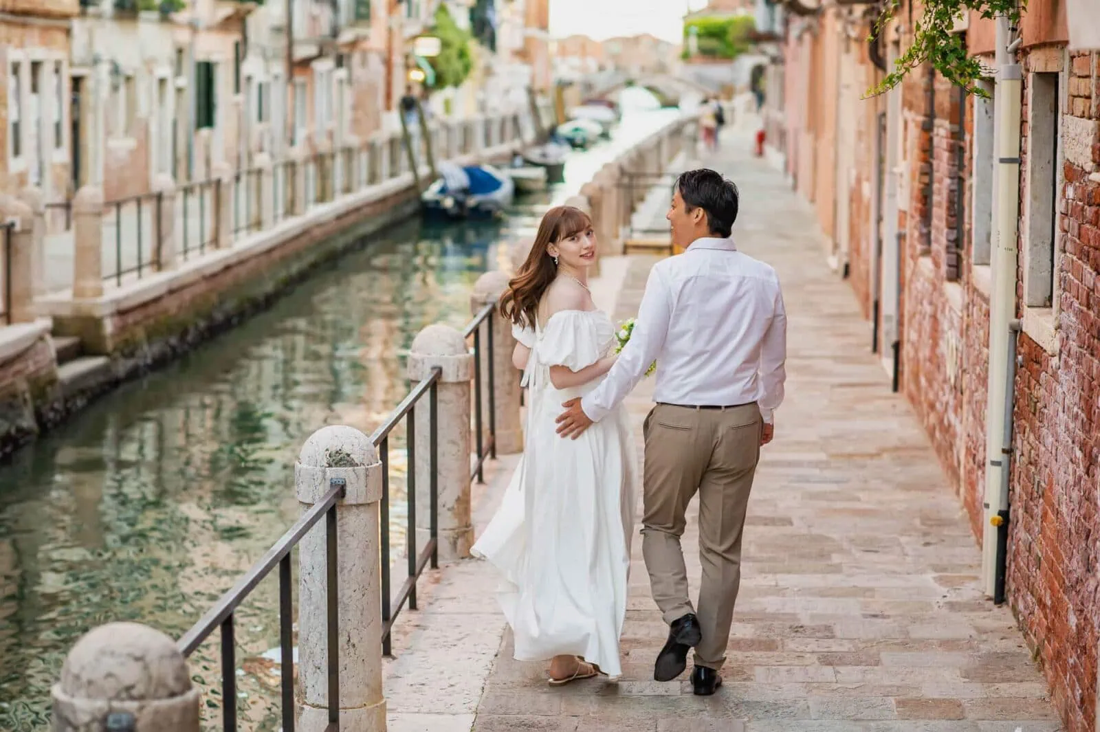 Engagement photos in Venice featuring a couple walking hand in hand along a canal in Dorsoduro.